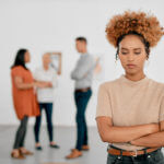 Shot of a young businesswoman being excluded from her colleagues in a modern office